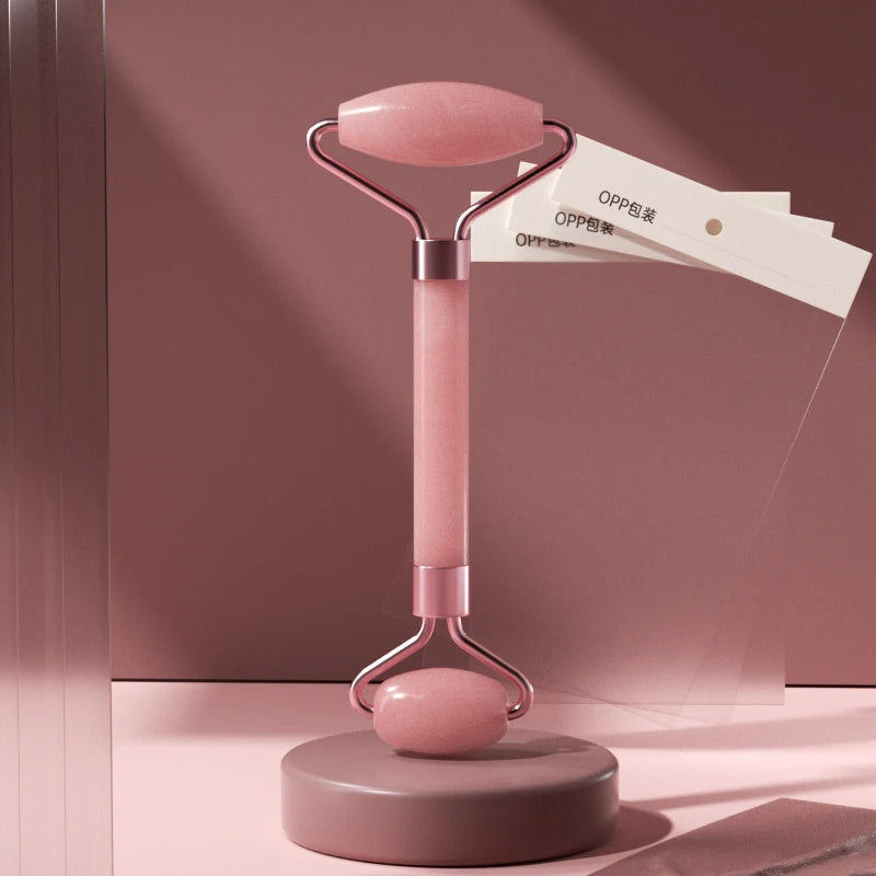 Facial massage roller with pink handle, oval top stone plate, and small base roller