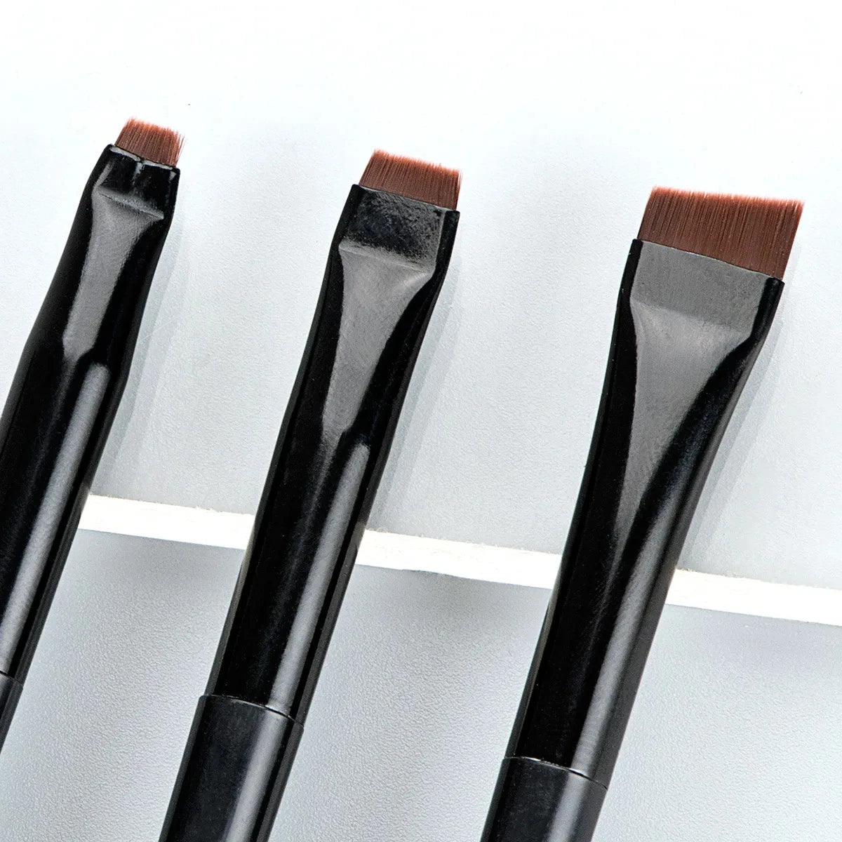 Eyeliner and eyebrow makeup brushes, flat angled heads with brown bristles