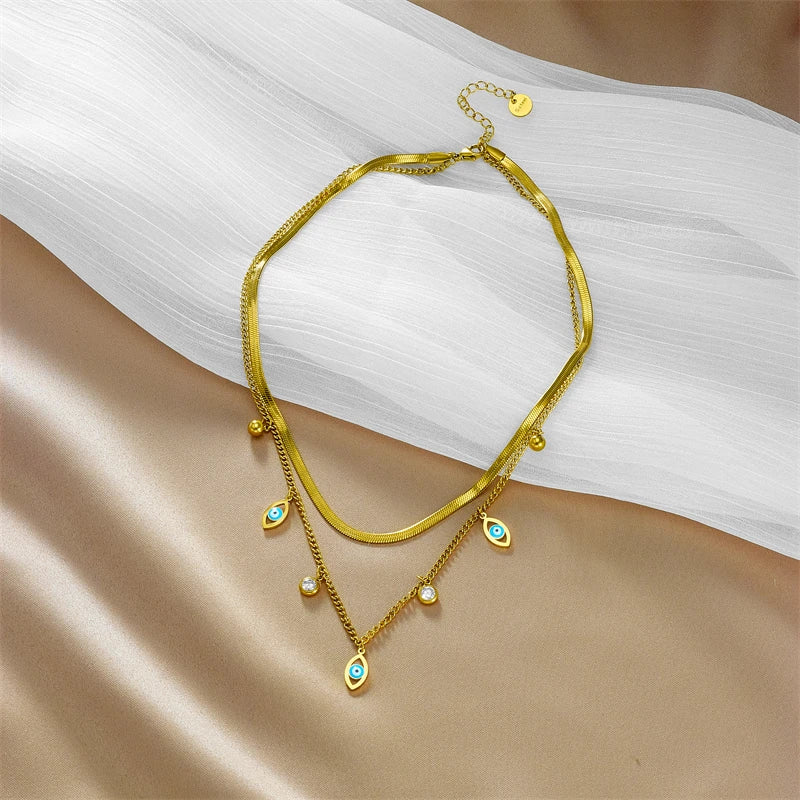 Gold-tone double-layer snake chain necklace with blue evil-eye charms and small round beads