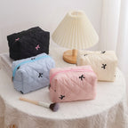 Quilted cosmetic bags in black, sky blue, pink, and cream with bow embroidery