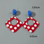 Square drop earrings with white polka dots and blue acrylic domes; geometric cutout center