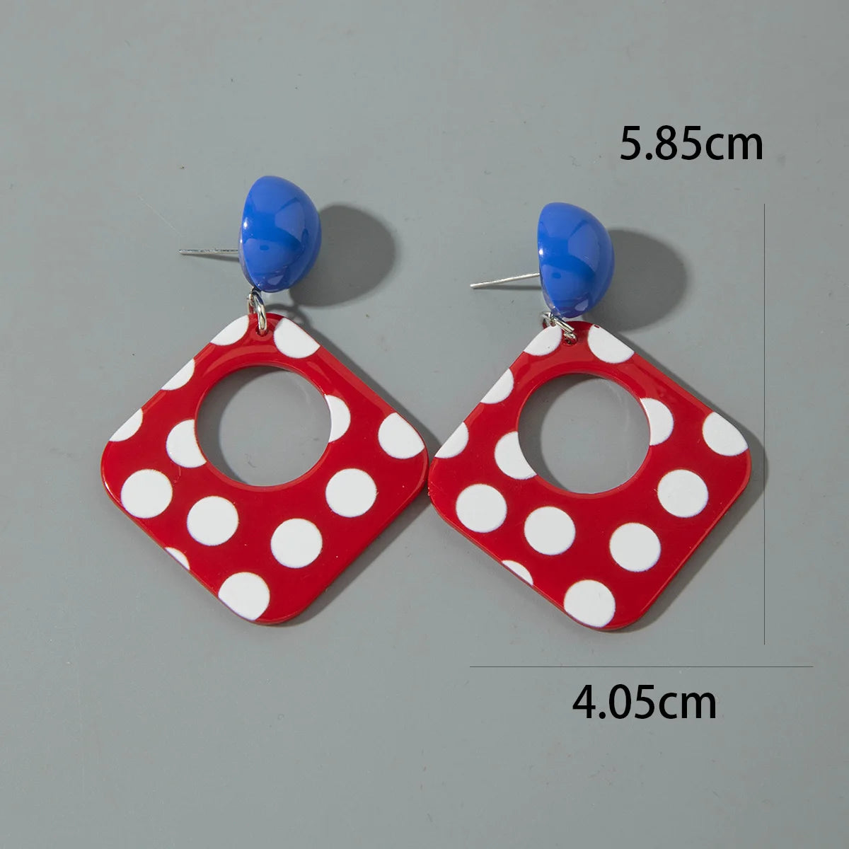 Square drop earrings with white polka dots and blue acrylic domes; geometric cutout center