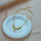 Gold-tone charm necklace with coin pendants and blue zircon detail