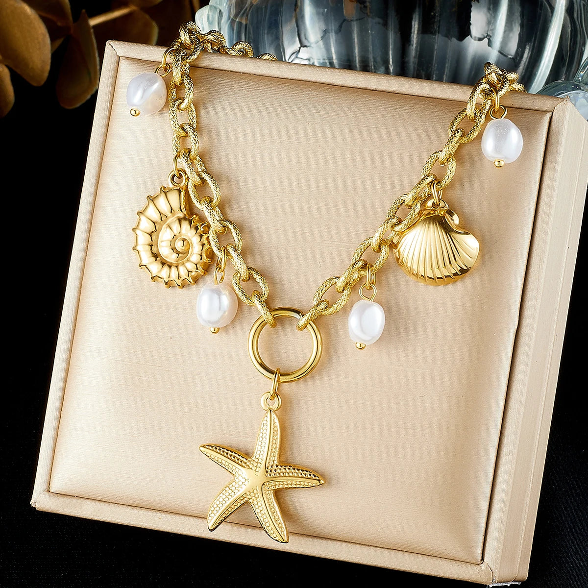 Gold-tone charm necklace with starfish pendant, seashell charm, and white pearl drops