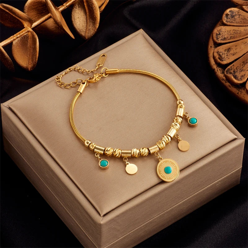 Gold-tone charm bracelet with green stone beads and round disc pendants