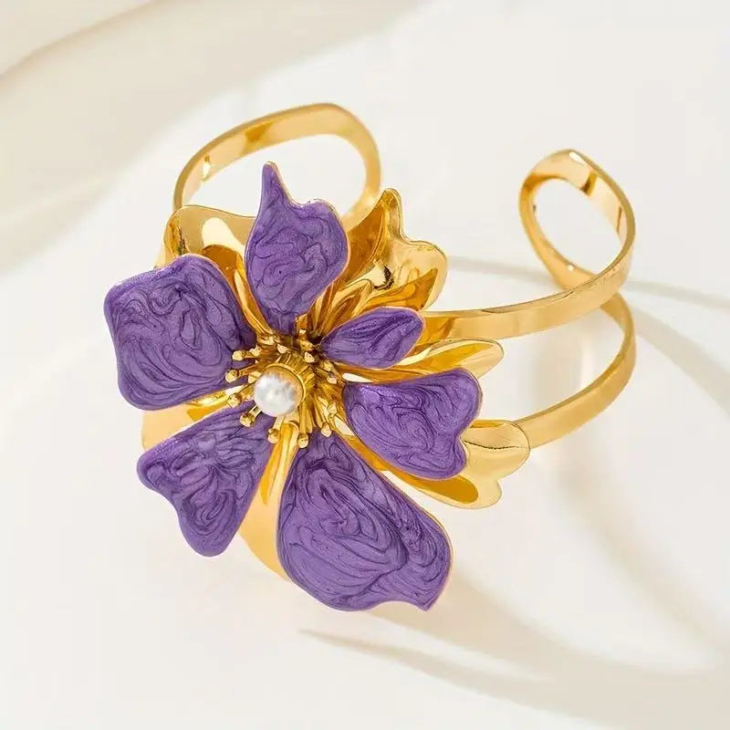 Flower cuff bangle bracelet with gold-tone band and purple enamel flower with pearl center.