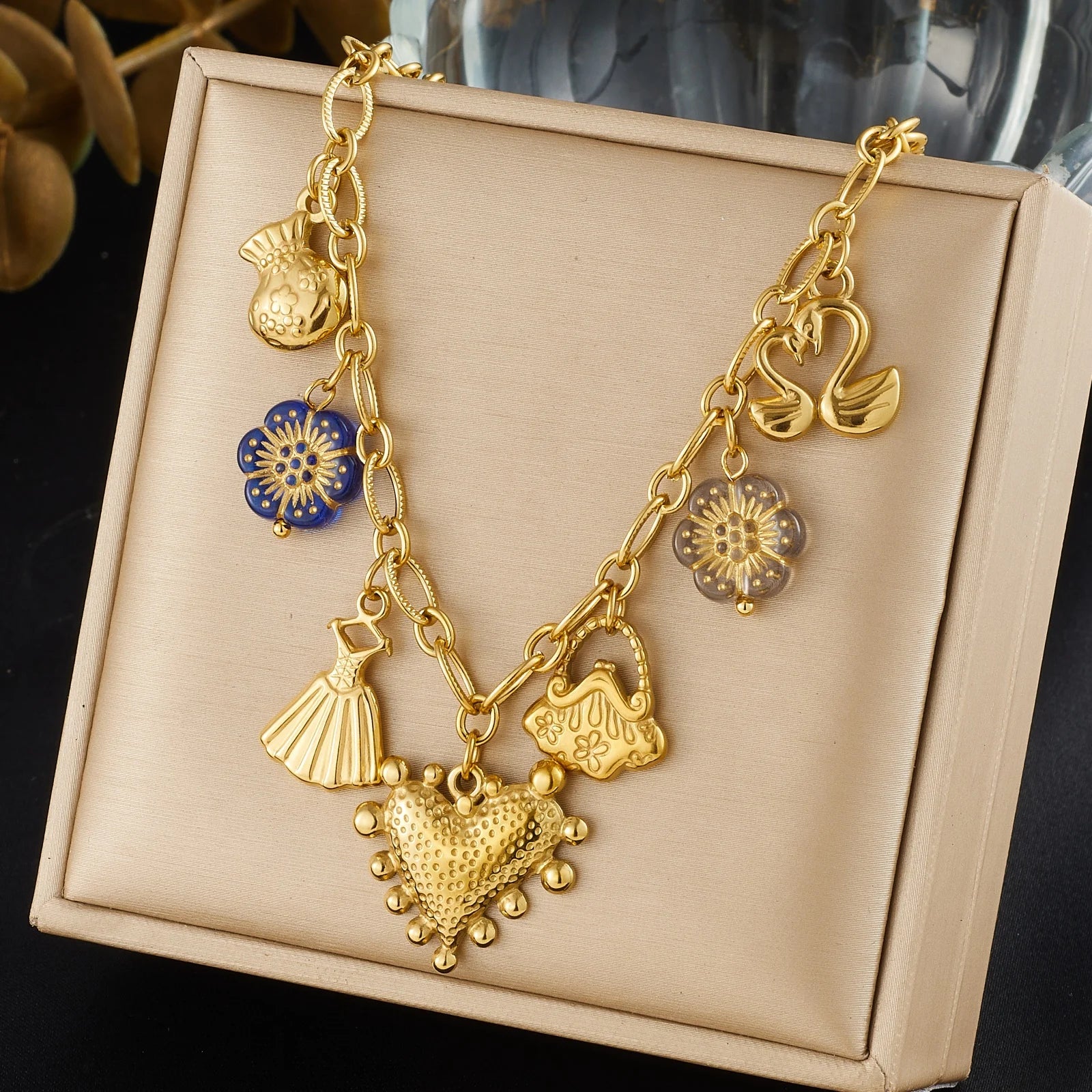 Gold-tone multi-pendant necklace display with heart, tassel, bow, and blue flower charms