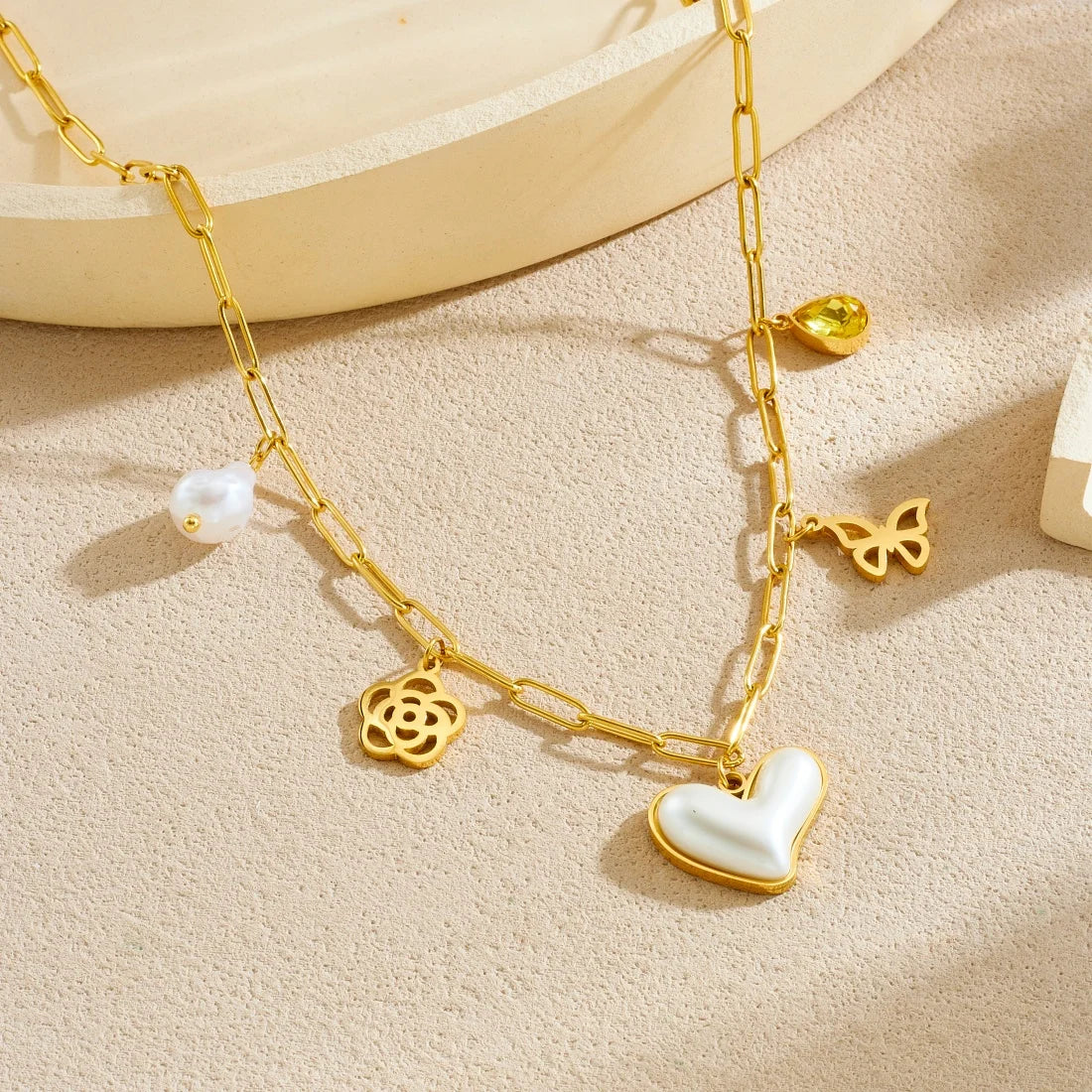 Gold-tone pendant necklace with pearl drop, heart charm, butterfly link, flower charm