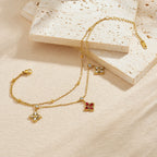 Gold-tone chain bracelet with red flower pendant and three white crystal flower charms