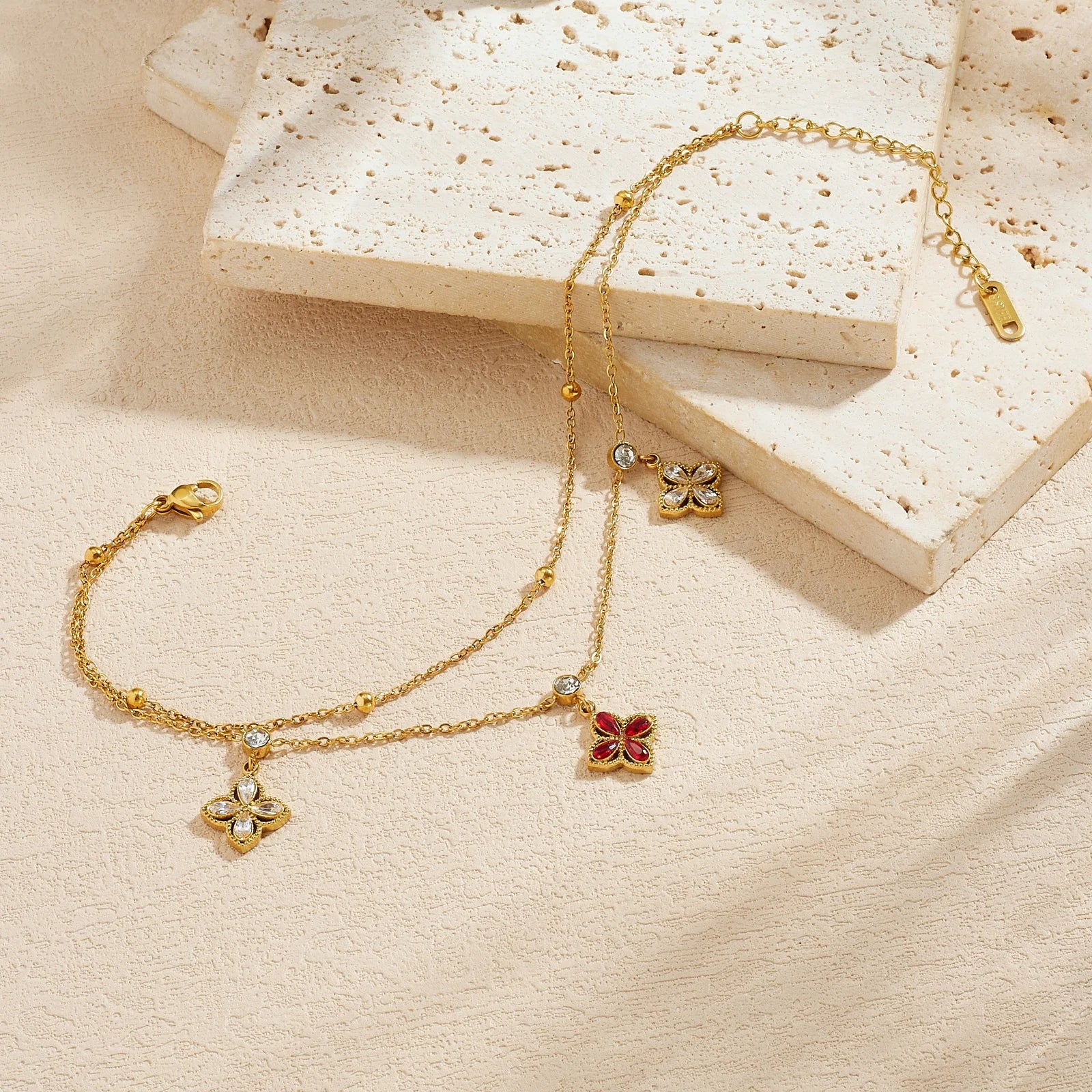 Gold-tone chain bracelet with red flower pendant and three white crystal flower charms