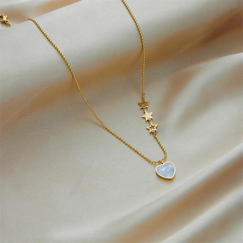 Gold-tone star charm pendant necklace with small heart at the bottom