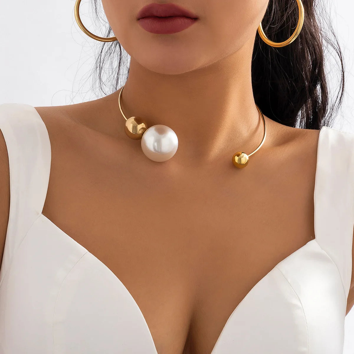 Gold-tone collar necklace with round white pearl bead centerpiece and small gold caps