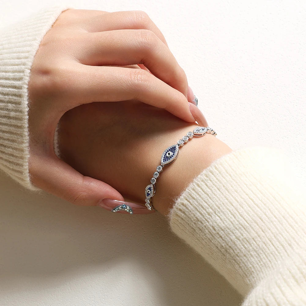Sterling silver evil eye bracelet on wrist with blue oval centerpiece and crystal links
