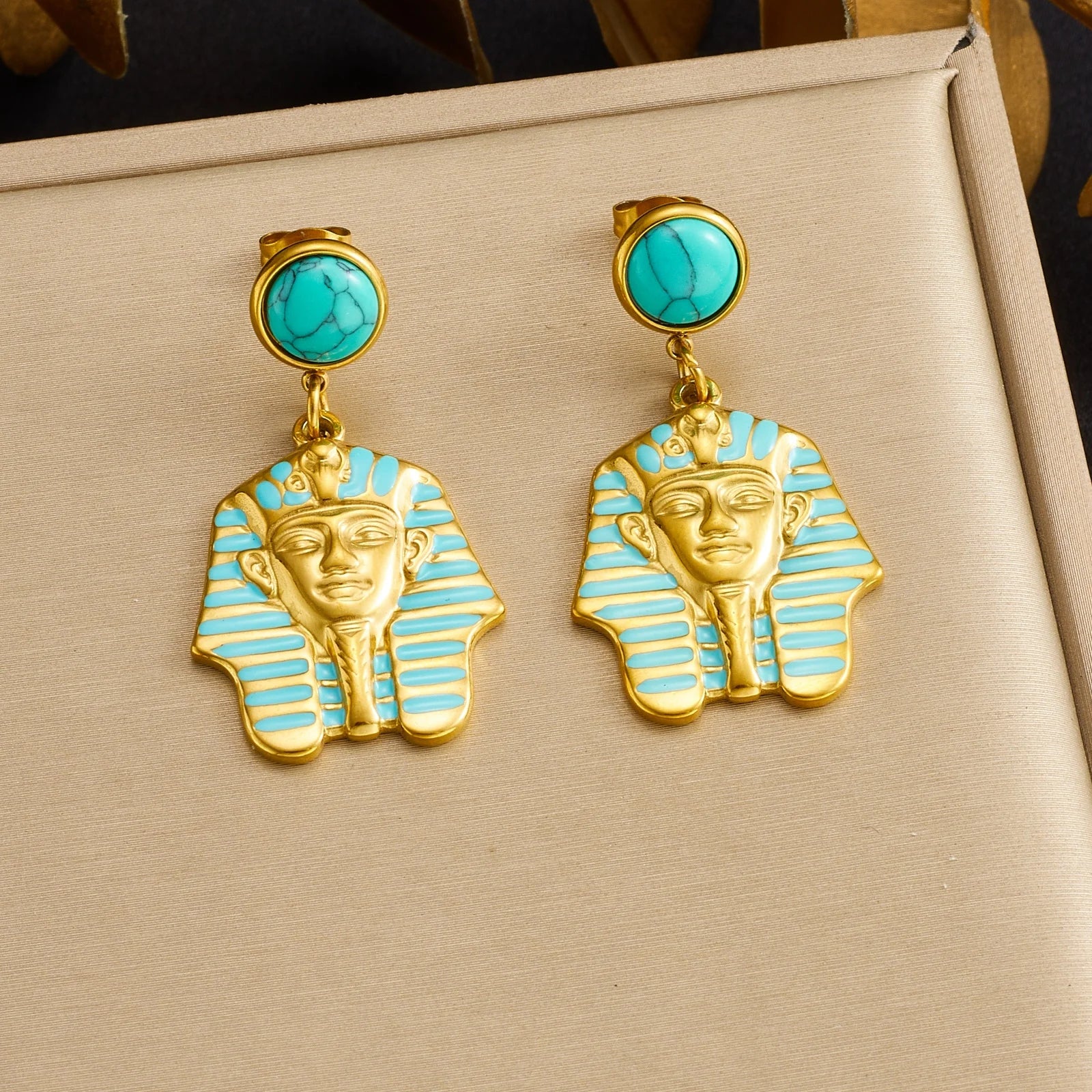 Gold-tone turquoise stud earrings with blue striped pharaoh face drop charms