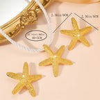Gold starfish charm earrings with glittery texture on a cord