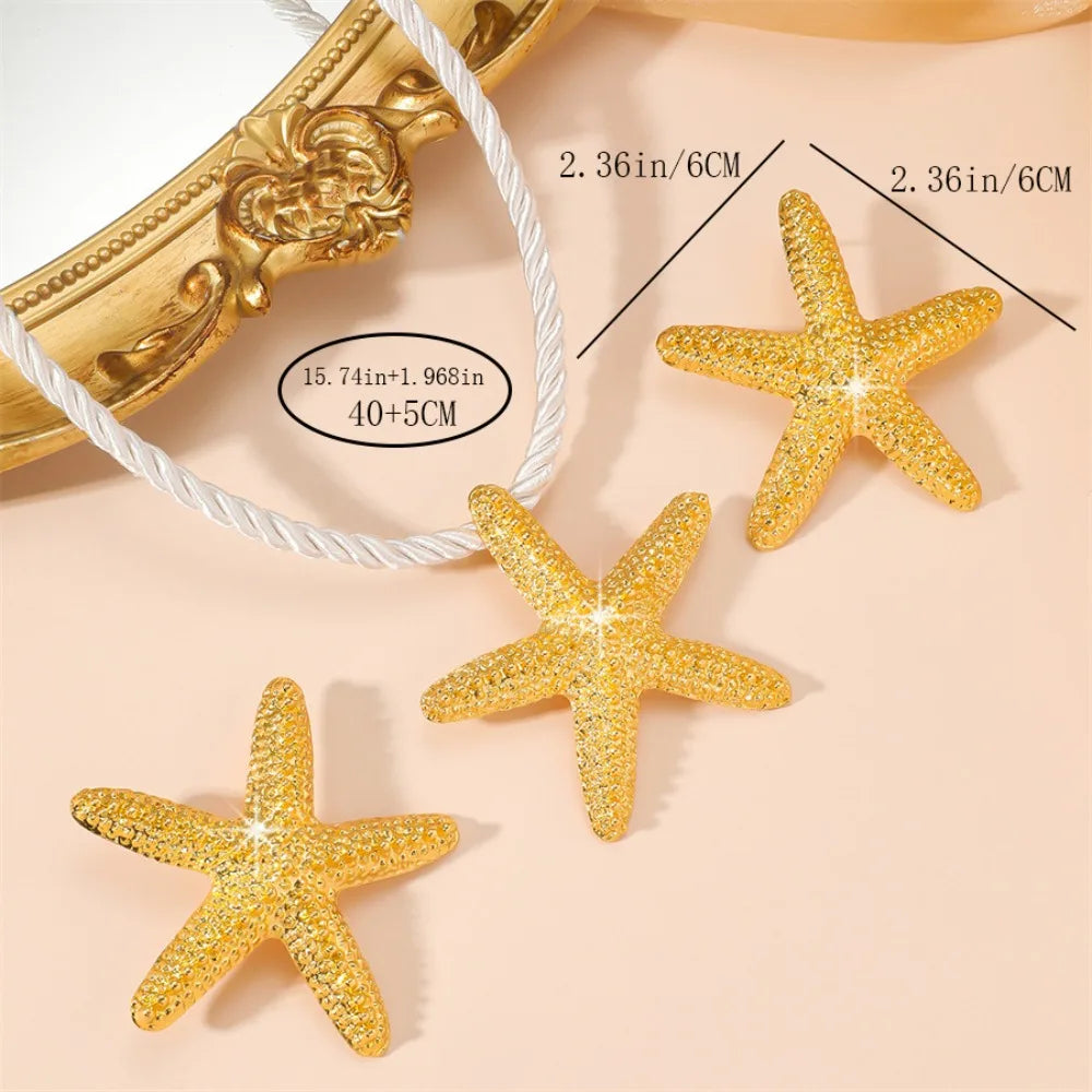 Gold starfish charm earrings with glittery texture on a cord