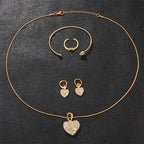 Gold heart pendant necklace with matching bangle, hoop earrings, and small ring