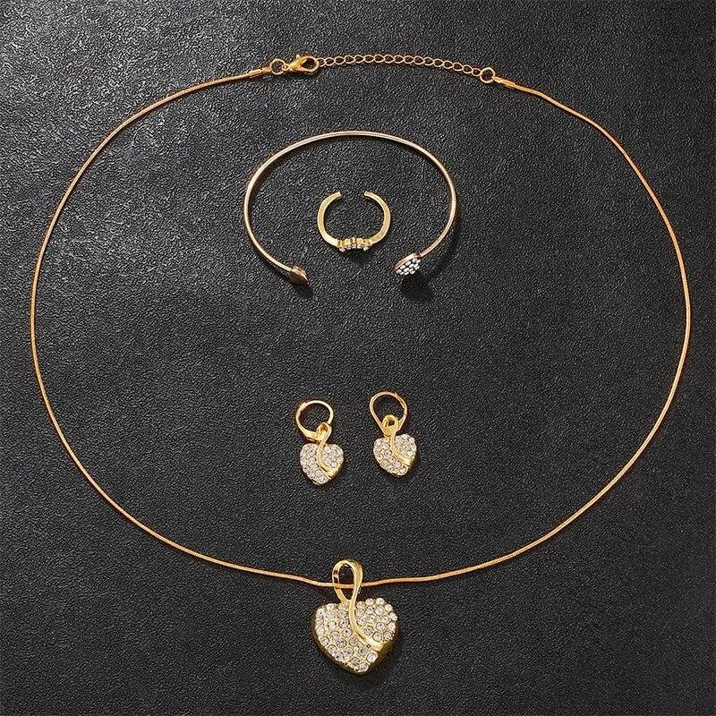 Gold heart pendant necklace with matching bangle, hoop earrings, and small ring