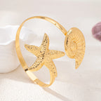 Gold starfish arm cuff with textured starfish and round shell disk centerpiece