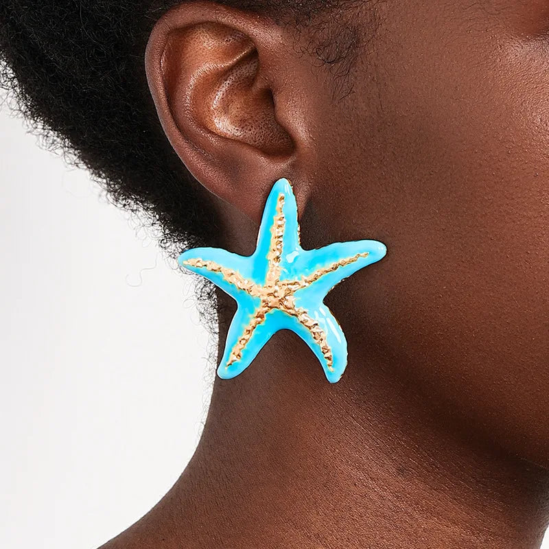 Starfish stud earrings with blue enamel starfish worn on ear