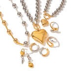 Heart charm jewelry set with layered ball chains, rings, and earrings in gold and silver