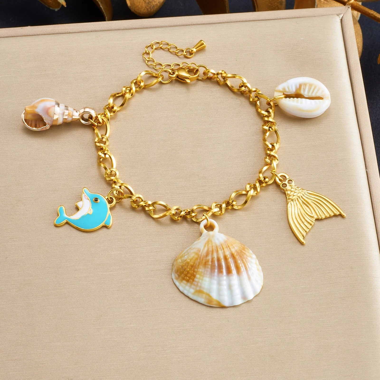 Gold-tone shell charm bracelet with blue dolphin, seashell, and gold fin charms