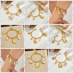 Gold-tone ocean charm bracelet with starfish and seashell charms, worn close-up