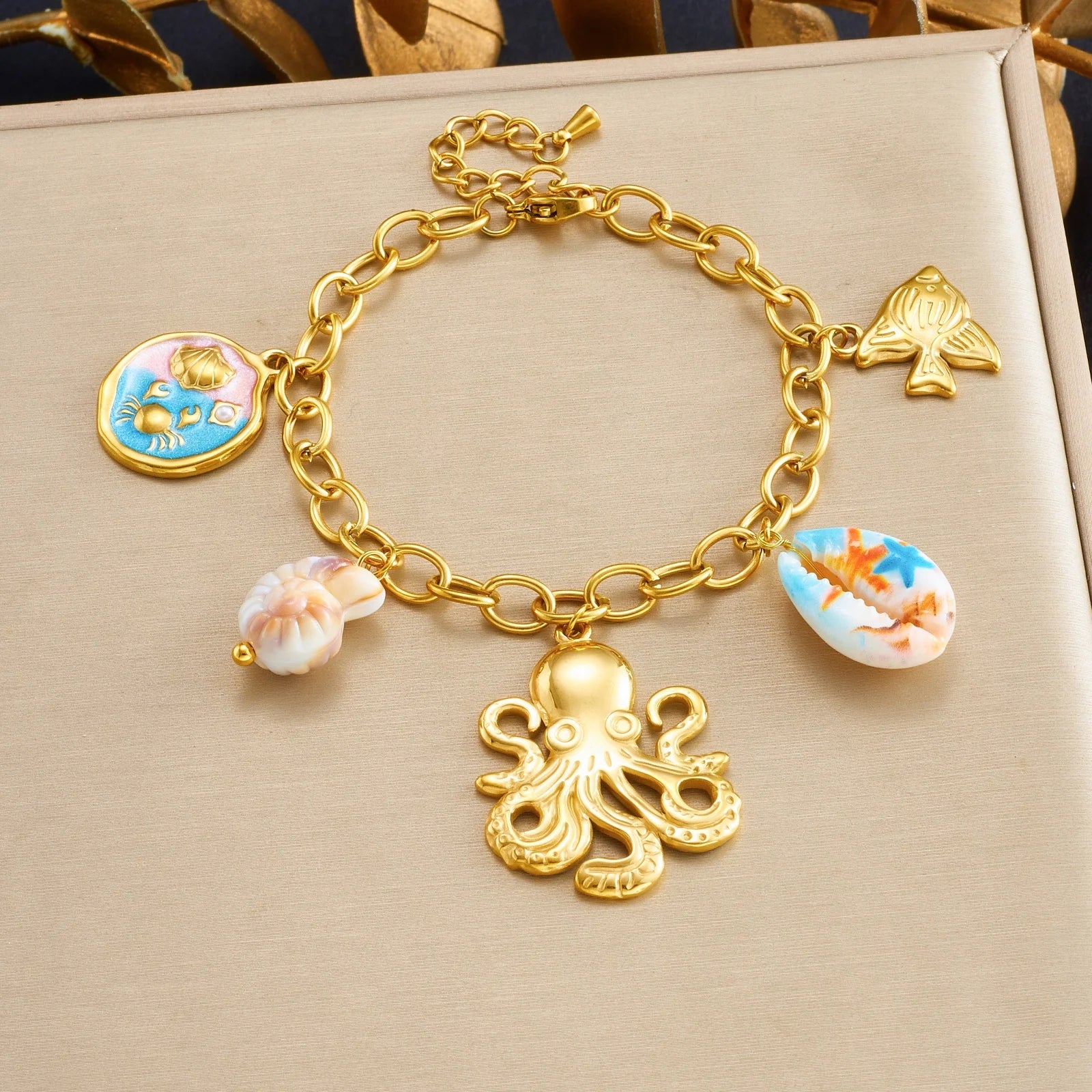 Gold-tone shell charm bracelet with octopus pendant and blue enamel shell and bow charms.