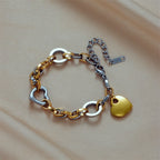 Two-tone chain bracelet with gold heart charm, silver heart links, and extender clip