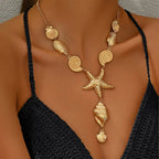 Gold starfish center necklace with spiral shell discs, scallop shells, and long pendant charm