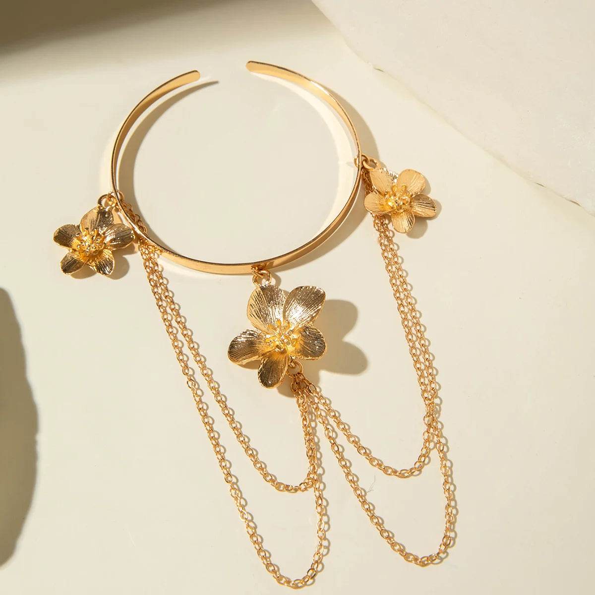 Gold four-petal flower upper arm bracelet with dangling chains and flower drops
