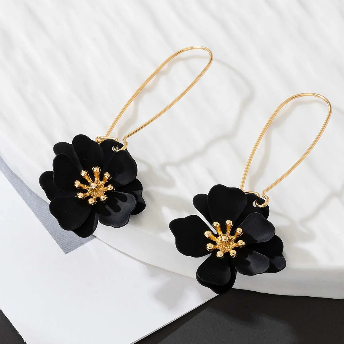Floral stud earrings with layered black flower petals and gold-tone hooks