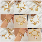 Gold-tone ocean charm bracelet with dangling seashell and fish charms, worn on wrist