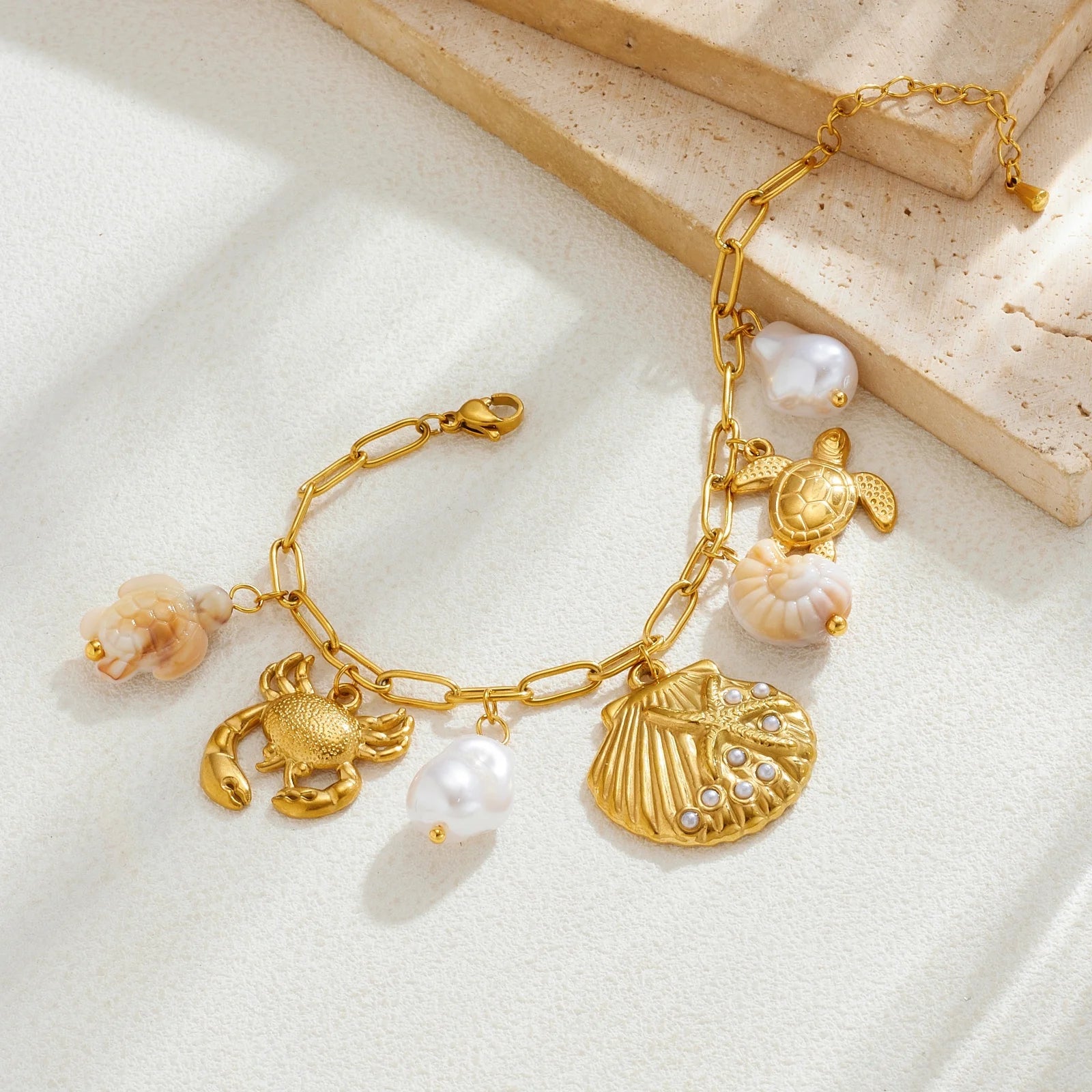 Gold-tone ocean charm necklace with scallop shell pendant, turtle and crab charms, pearl beads