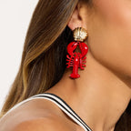 Gold-tone lobster dangle earrings with red lobster charm and scallop shell top
