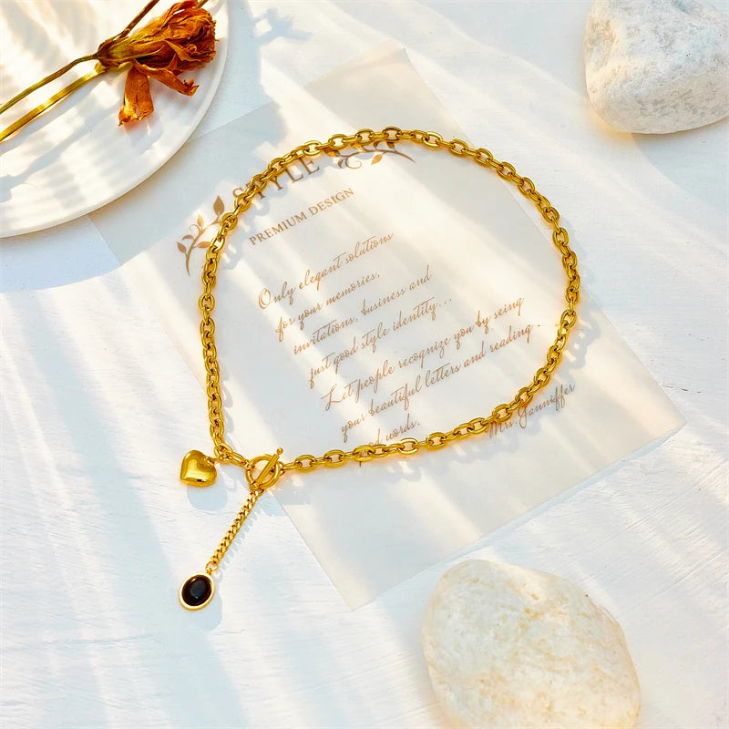 Gold-tone heart pendant necklace with round black stone drop and small heart charm