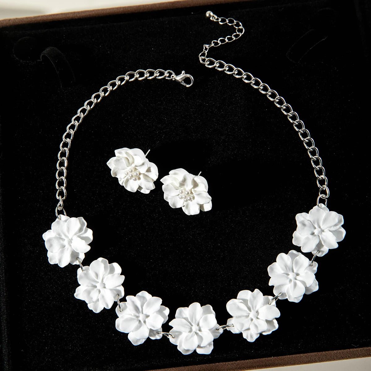 White flower stud earrings and white flower necklace on black jewelry tray