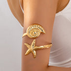 Gold-toned shell-and-starfish arm ring with textured round shell disk and starfish charm