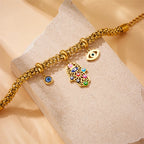 Gold-tone beaded charm bracelet with blue eye charm and colorful hamsa hand pendant