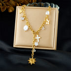 Gold-tone charm necklace in jewelry box: cross pendant, star charms, pearl beads