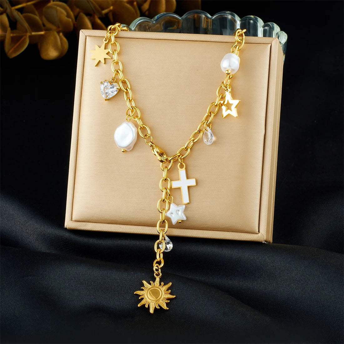 Gold-tone charm necklace in jewelry box: cross pendant, star charms, pearl beads
