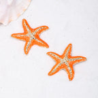 Starfish stud earrings with orange starfish and silver-tone textured detail