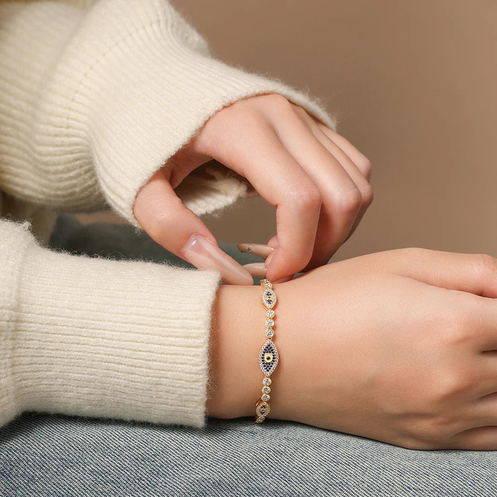 Silver-tone evil eye bracelet on wrist with blue oval center and pavé bead links