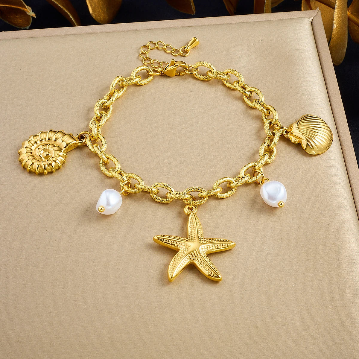 Gold-tone charm necklace with seashell and pearl drops, featuring a starfish pendant
