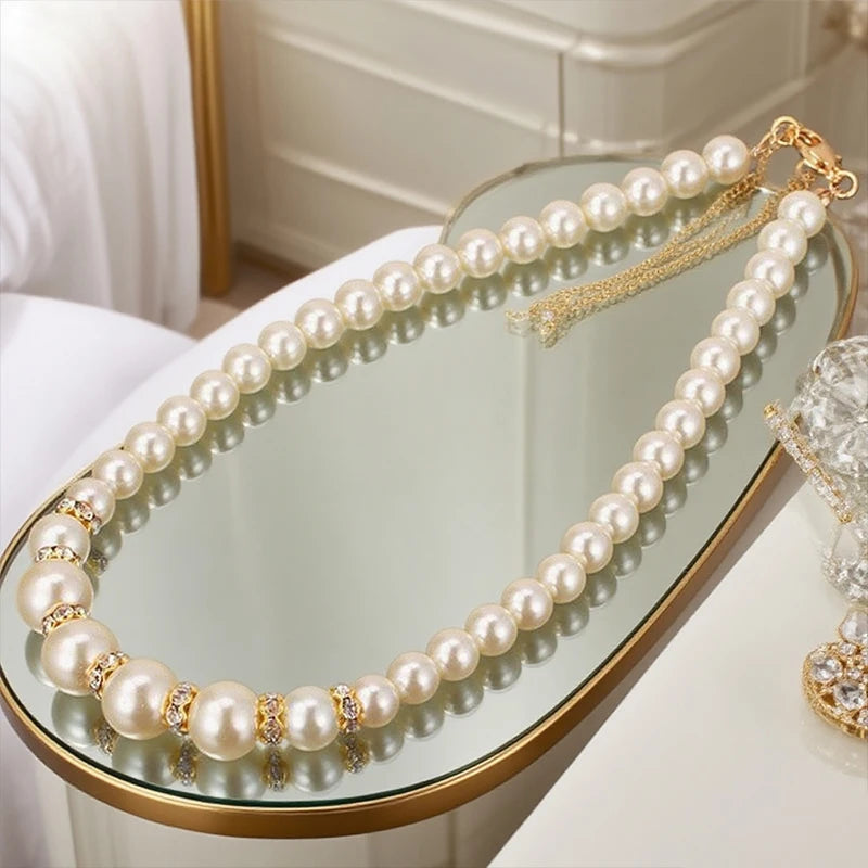 Pearl necklace with round beads, gold-tone clasp, and small dangling chain