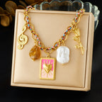 Gold-tone charm necklace with pink heart square pendant, white pearl, amber drop, leaf dangles