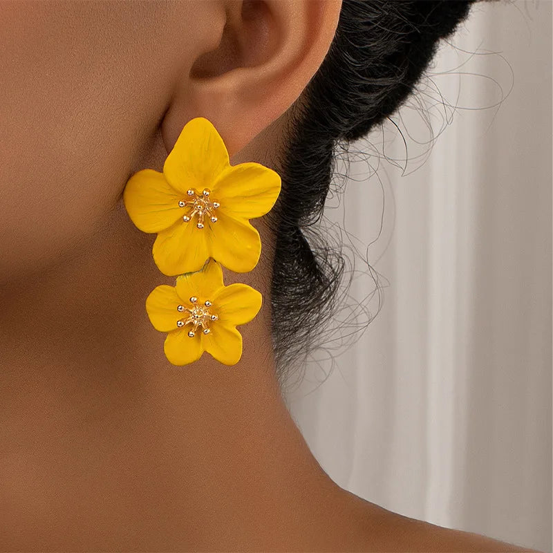 Yellow double-layer flower dangle earrings on ear with gold-tone star centers