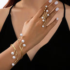 Gold-tone pearl ring with dangling beads and pearl bracelets on fingers