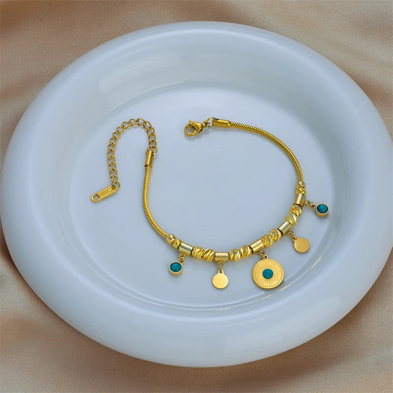 Gold-tone charm bracelet with green stone beads and sunburst round pendant, toggle clasp