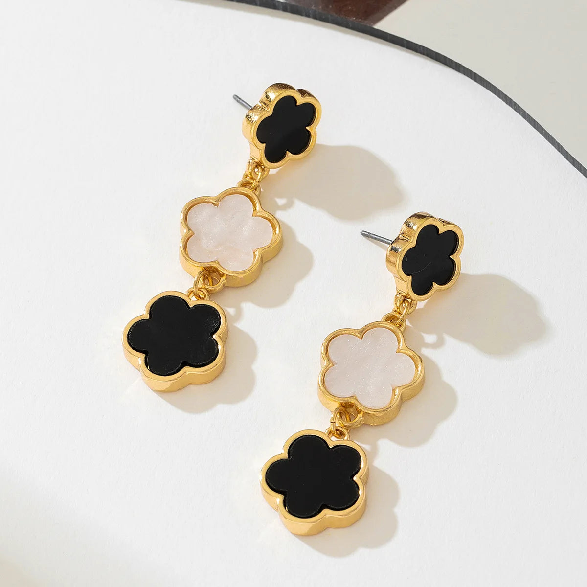 Five-petal flower long drop earrings, gold-tone with alternating white and black enamel clover charms